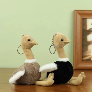 Porte-clés autruche en peluche gris et noir posés sur une surface en bois