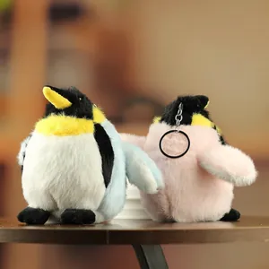 Cute plush penguin keychains in blue and pink colors with metal ring on wooden surface