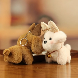 Detail of plush puppy keychains with plaid bows and bell collars on soft fabric