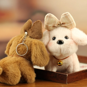 Detail of plush dog keychain with pink bow and metallic ring in a warm setting