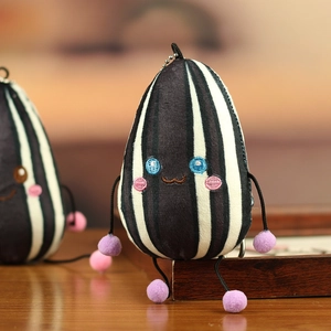 Macro-opname van pluche zonnebloempit sleutelhanger met strepen en paarse pompons