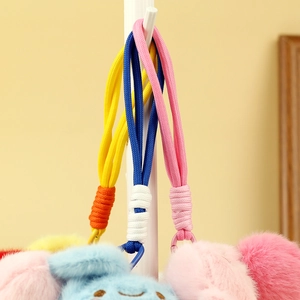 Detail of colorful braided lanyards and plush keychains with smiling blue face pendants