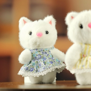 Détail macro du chaton en peluche blanc avec robe à fleurs violettes et dentelle