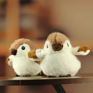 Close-up of two plush sparrow bird charms with soft textures on a warm wooden surface