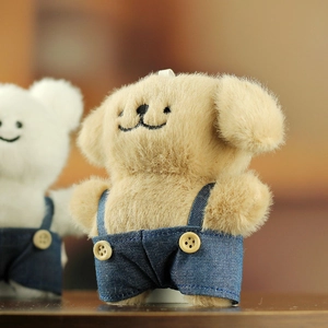 Gros plan d'un chiot en peluche portant une salopette en jean bleu avec boutons