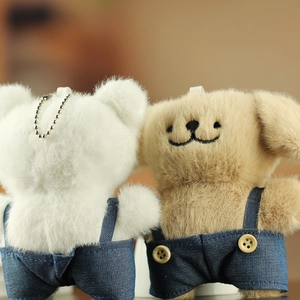 Gros plan de porte-clés chiot en peluche avec salopette en jean et chaîne