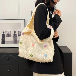 Off-white plush tote bag with colorful flower embroidery shown from a side view on model