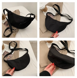 Detail view of a black nylon crescent crossbody bag with adjustable wide shoulder strap