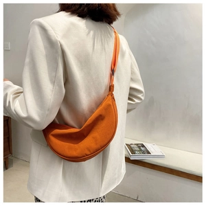 Orange crescent crossbody bag detail showing adjustable wide strap on a female model