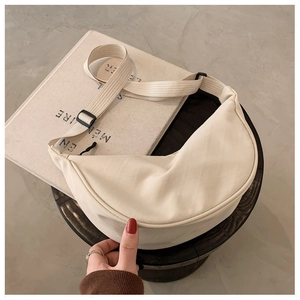 Detail of beige half-moon crossbody bag with adjustable wide strap and nylon texture