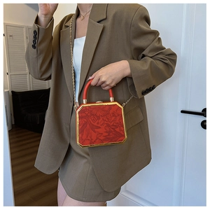 Detail of red floral embossed box bag with gold metal frame and chain handle