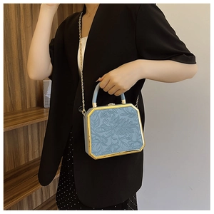 Detail of octagonal box bag with floral embossing and elegant gold metal frame accents