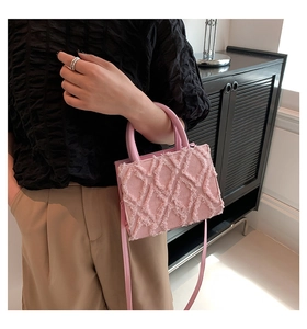 Detailed macro of pink quilted tote bag showing frayed fabric texture and premium stitching