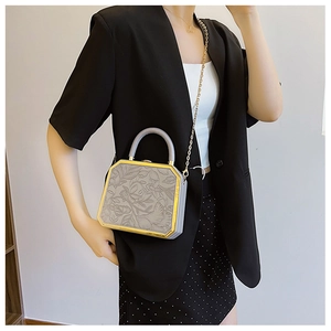 Detail of grey hexagonal handbag with 3D floral embossing and gold chain strap