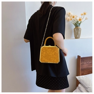 Detailed view of yellow floral embossed box bag with gold frame and chain strap