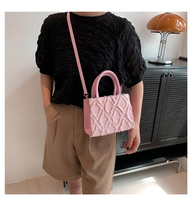Close-up of pink tote bag with tassel diamond pattern and gold-tone metal hardware details
