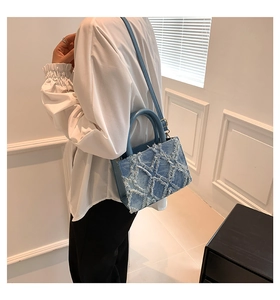 Detail of blue denim tote bag featuring distressed star patterns and leather handles