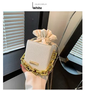 Dettaglio della mini borsa a secchiello bianca intrecciata con coulisse e catena d'oro