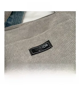 Macro shot of grey corduroy fabric texture with a black Fashion Instinct woven label