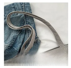 Detail shot of wide corduroy shoulder strap with metal chain hook on grey tote bag