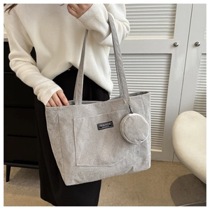 Detail of light gray corduroy tote bag showing textured fabric and fashion logo label