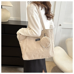 Detail of beige corduroy tote bag showing velvet texture and round coin purse attachment