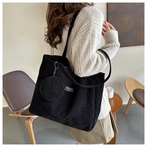 Detail of black corduroy tote bag with fashion label and matching round coin purse