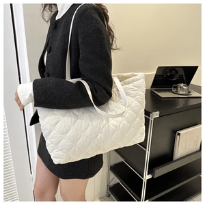 Detailed view of a white quilted tote bag featuring large diamond stitching and soft texture