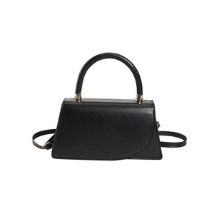 Minimalist black trapezoid handbag with gold metal hardware and adjustable shoulder strap