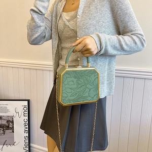 Octagonal green box handbag with gold floral relief and chain strap on a model