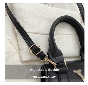 Détail de la boucle dorée réglable et du logo V sur le sac à bandoulière en cuir noir