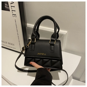 Detail of black mini crossbody bag with gold logo and triangular quilted pattern texture