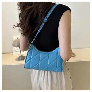 Detail of sky blue quilted shoulder bag with fine stitching on a minimalist model
