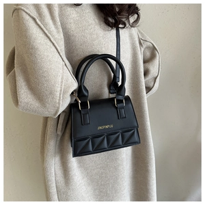 Detail of black crossbody bag featuring quilted patterns and golden metal ring handles