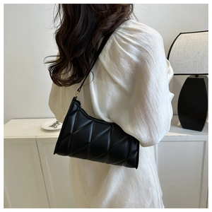 Detail of black quilted puffer underarm bag on model with elegant crescent shape