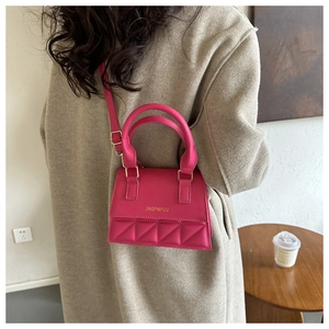 Detail of rose pink crossbody bag with diamond lattice stitching and gold branding