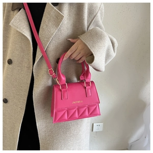 Hot pink quilted crossbody bag with gold buckle worn on a stylish beige coat outfit
