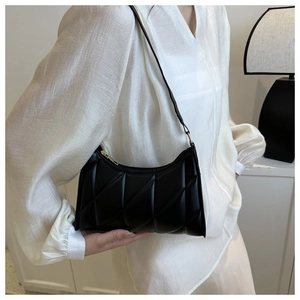 Detail of black quilted shoulder bag with gold zipper and matte leather texture
