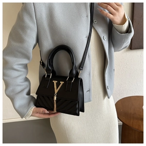 Détail du mini sac noir avec logo V doré, franges en chaîne et texture matelassée
