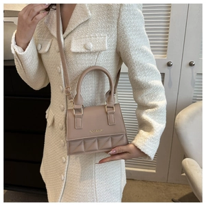 Detail of beige quilted leather crossbody bag with chain strap and top handle