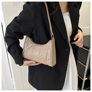 Close-up of beige quilted shoulder bag on model showing elegant texture and slim strap