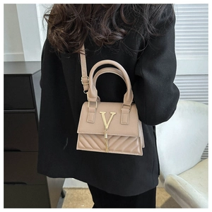 Détail du sac en cuir abricot avec texture matelassée et logo V doré avec pompon