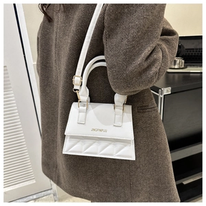 Close-up of white crossbody bag with quilted texture and gold-tone hardware detail