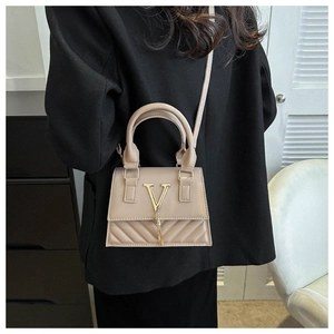 Détail du sac beige en similicuir avec motif en V et boucle en V dorée avec gland