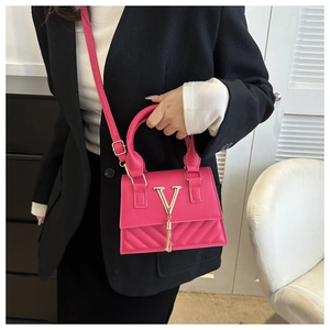 Dettaglio borsa fucsia con hardware in metallo a V dorato e decorazione nappa a frange