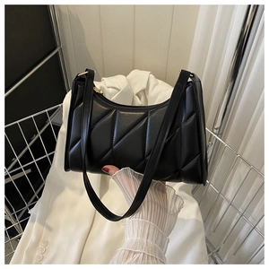Detail view of black quilted shoulder bag with geometric stitching and gold zipper