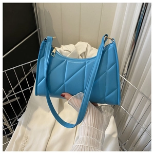 Close-up of bright blue quilted shoulder bag with geometric stitching and gold zipper detail