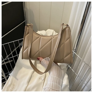 Detail of beige quilted shoulder bag with fine stitching and elegant leather texture