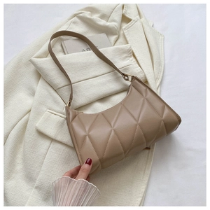Detailed view of coffee-colored quilted shoulder bag with diamond stitch on white blazer