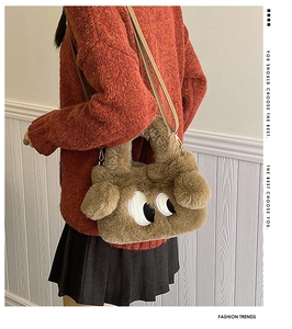 Détail du sac en peluche marron avec motif de grands yeux et bandoulière